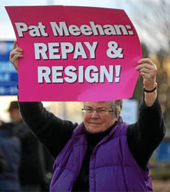 Female protester holding a sign, "Pat Meehan: REPAY & RESIGN!"