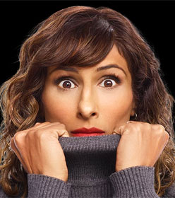Sarayu Blue in "I Feel Bad" TV show, pulling her turtleneck sweater up, obscuring chin and neck