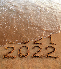 "2022" written in the sand, with a wave washing away "2021"