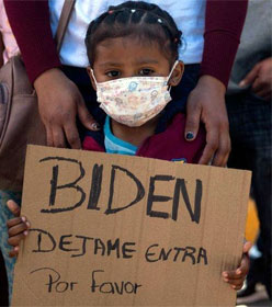 Girl holding sign pleading for entry at the border