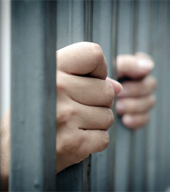 Hands clutching prison bars