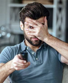 Man watching TV nervously