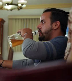 Man watching TV and drinking from a bottle