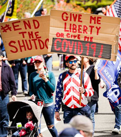 Protester holding sign, "Give me liberty or give me Covid-19"